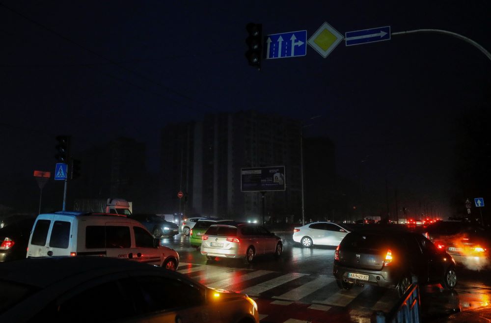 Autók haladnak el közvilágítás nélkül maradt épületek mellett áramszünet idején Kijevben